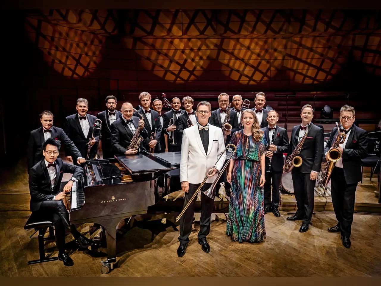 Mitglieder des Glenn Miller Orchester in Abendkleidung vor Flügel