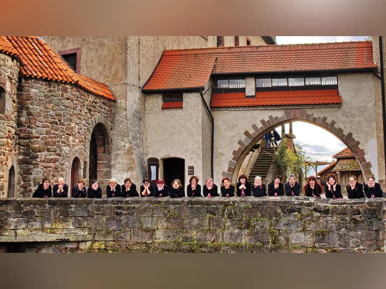 Chorsänger sind über eine Mauer der Leuchtenburg gebeugt