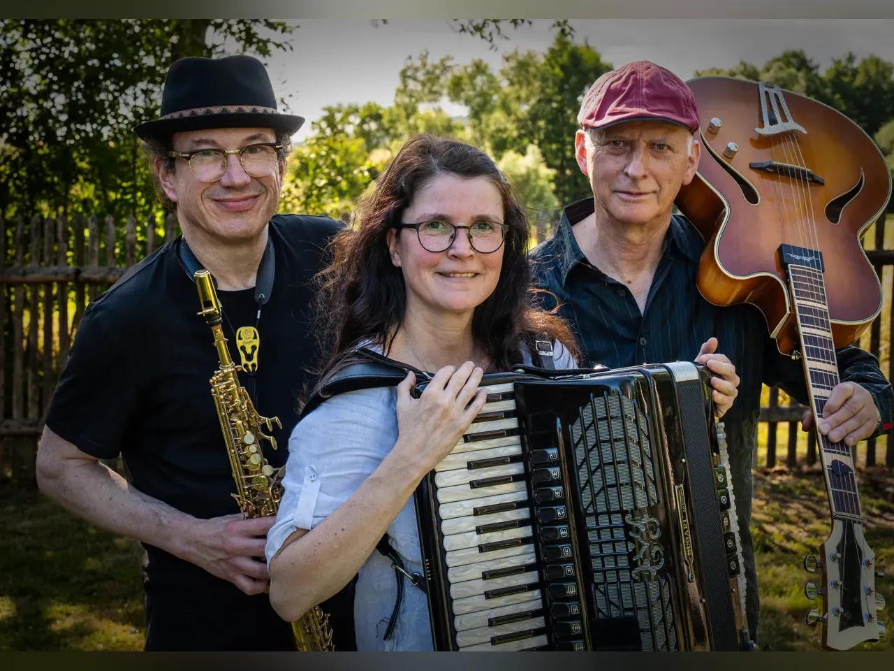 Mitglieder des Dirk Wasmund Trios mit ihren Instrumenten in einem Garten