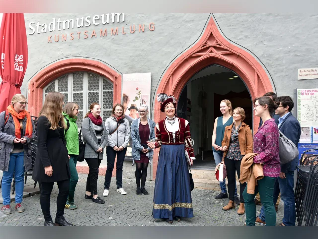 Kostümierte Stadtführerin mit einer Reisegruppe vor dem Stadtmuseum Jena