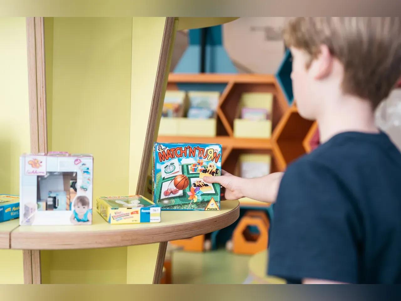 ein Junge nimmt ein Spiel aus dem Regal