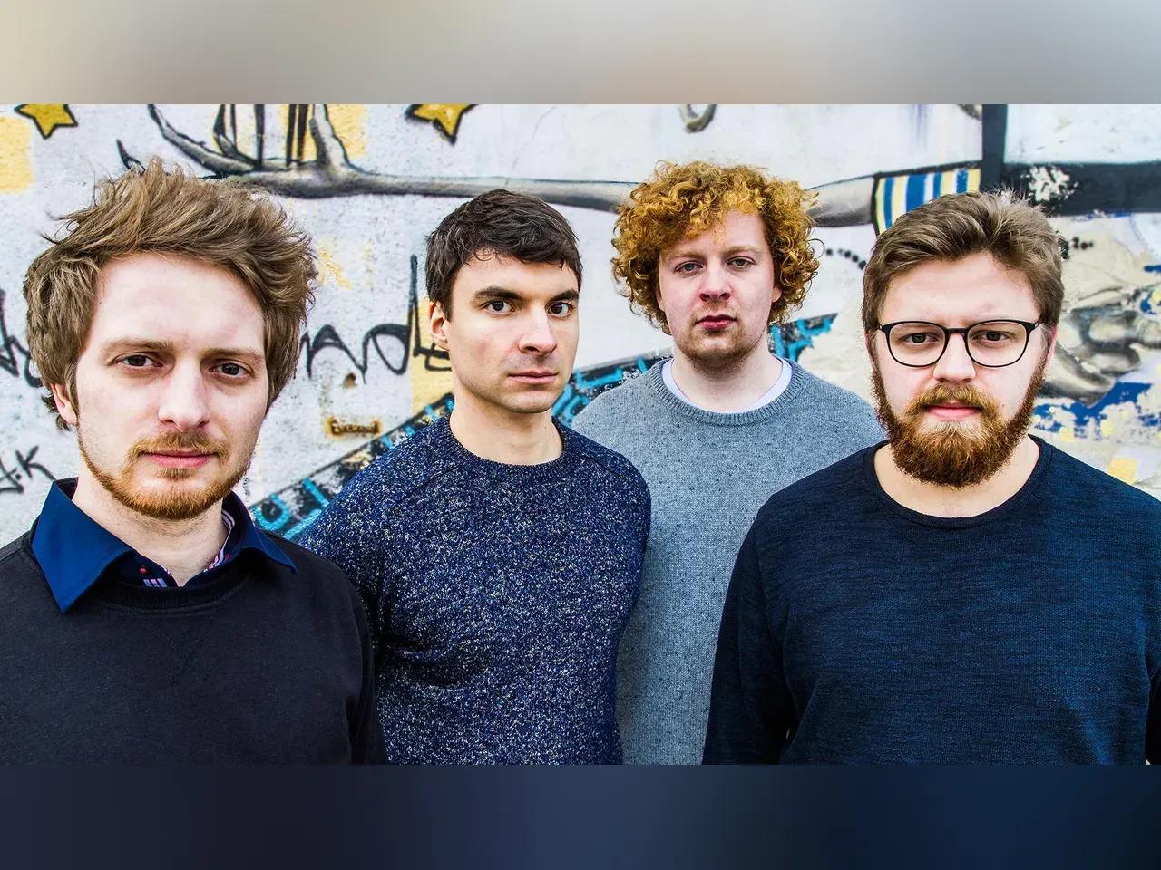 Die vier Musiker vor einer bunt bemalten Mauer