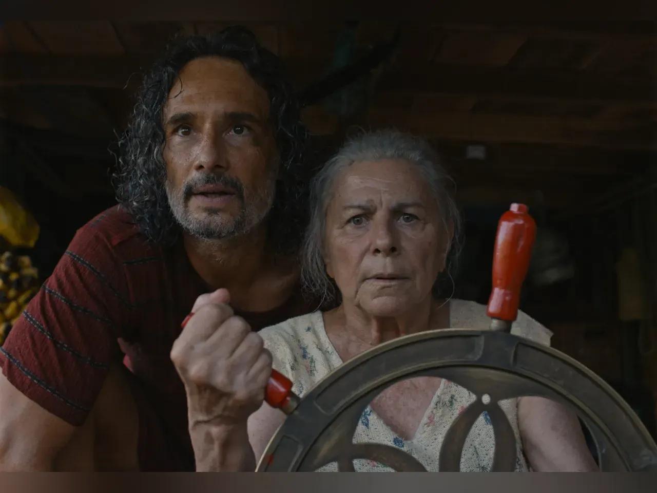 Filmszene aus "Das tiefste Blau": ältere Frau am Steuer eines Ruders, ein Mann sieht ihr über die Schulter