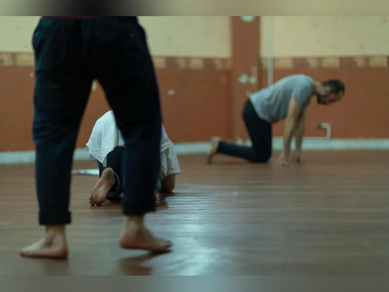 Schauspieler:innen bei körperlichen Übungen auf einem Parkettboden