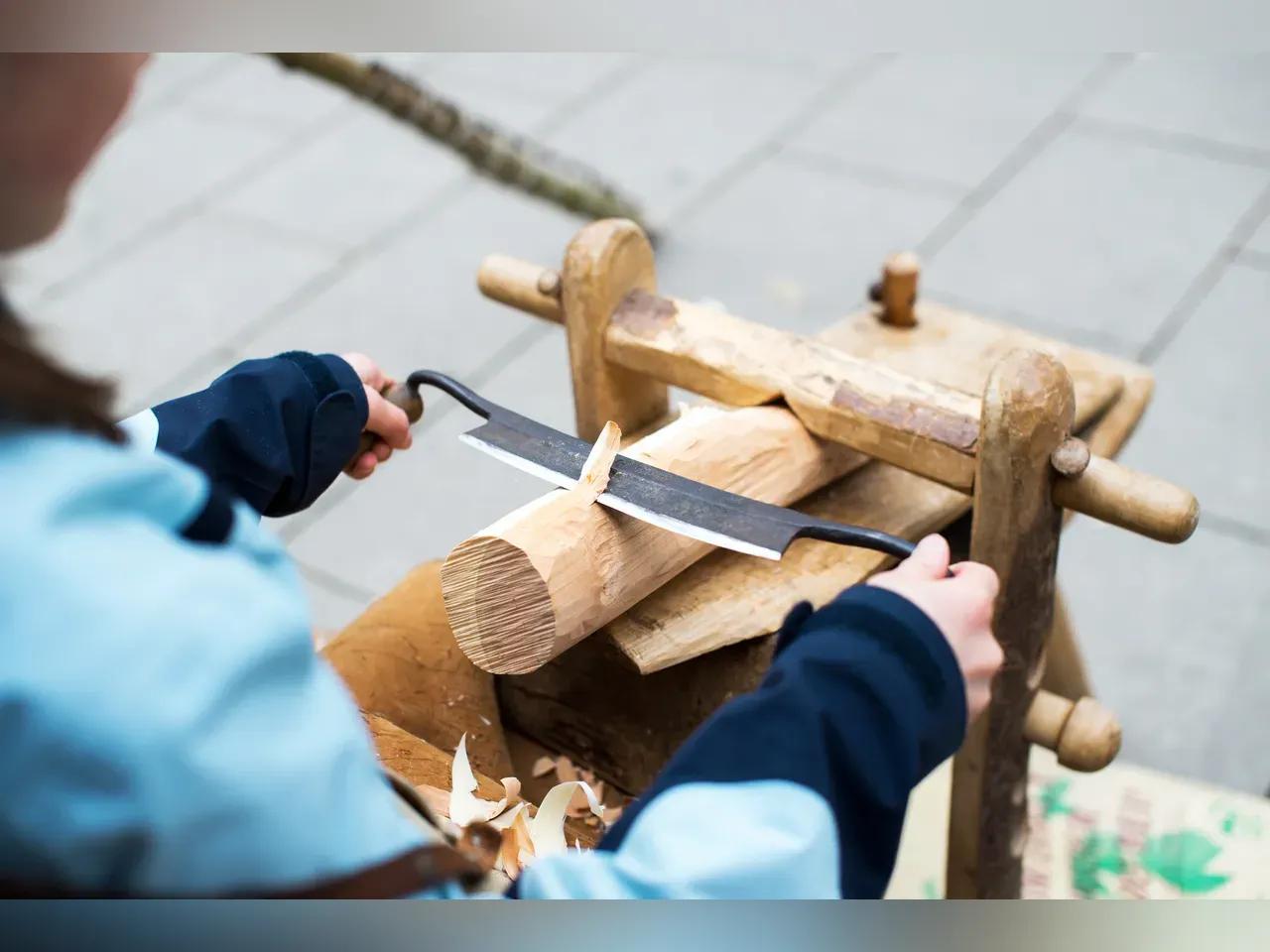 Ein Kind probiert sich am Bearbeiten eines Holzstücks aus.