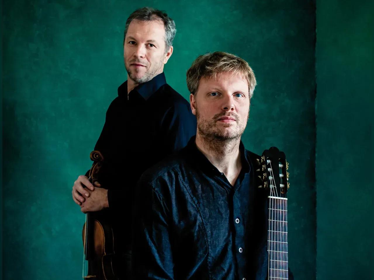 2 Musiker mit Gitarre und Geige vor einer grünen Wand