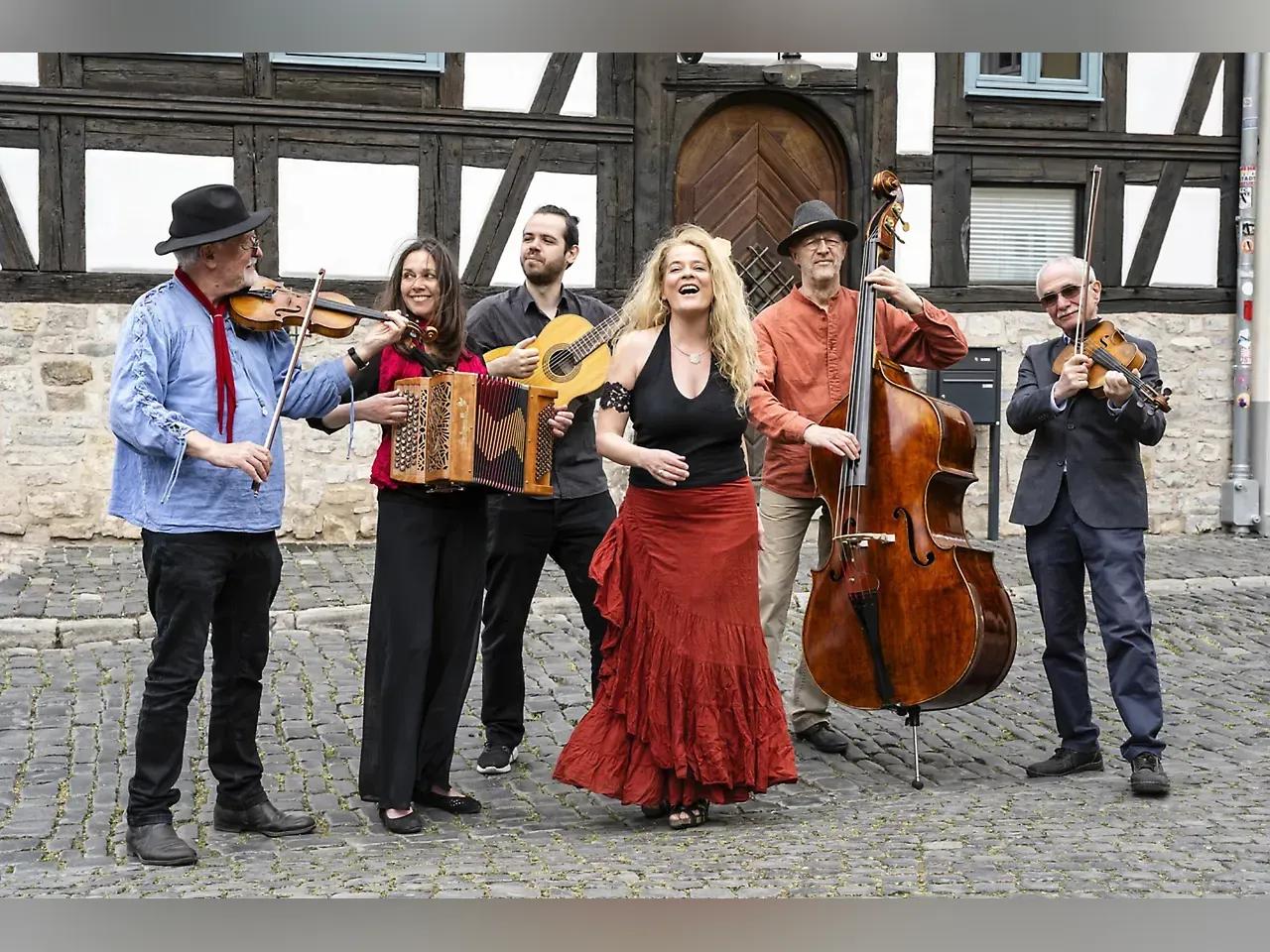 Menschen mit Instrumenten vor einem Fachwerkhaus