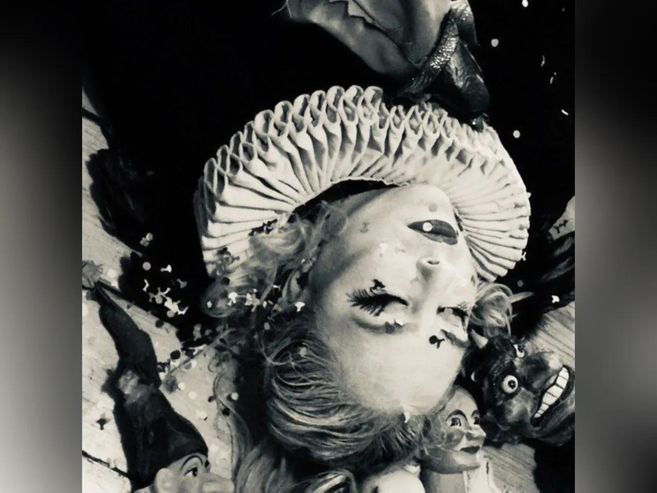 Frau liegt mit geschlossenen Augen, auf die Konfetti regnet, mit einem Shakespeare-Kragen inmitten von Handpuppen