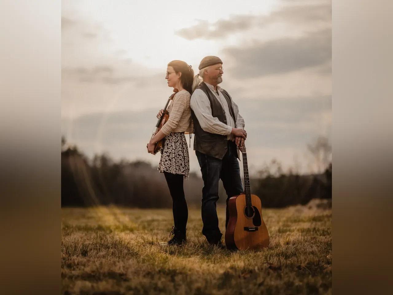 Musiker:innen auf einem Feld mit Geige und Gitarre