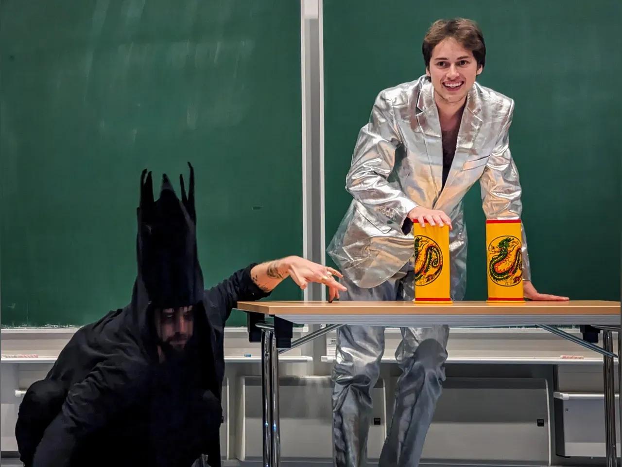 Menschen in Kostümen vor einer Tafel