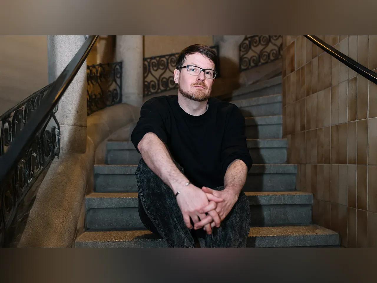 Robert Seidel sitzt auf einer Treppe im Volkshaus Jena