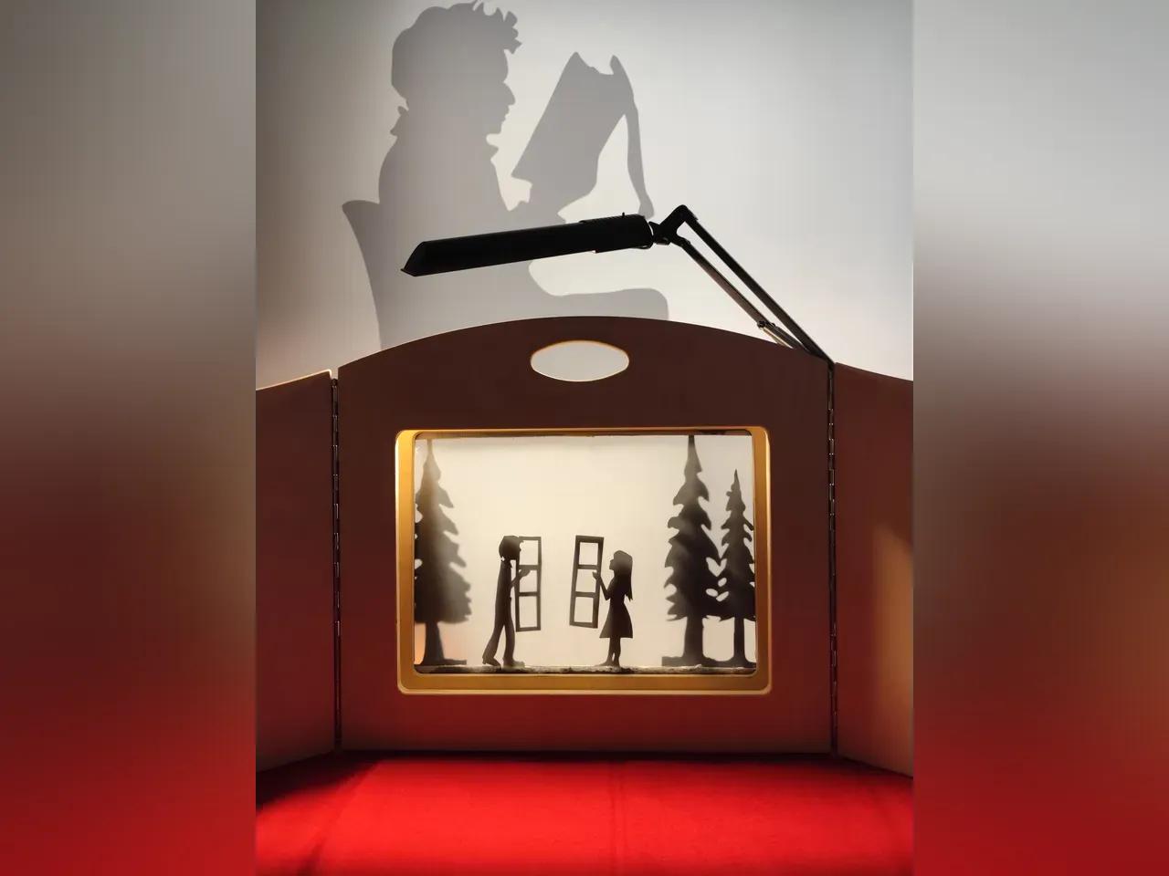 Auf dem Foto ist eine kleine Schattentheaterbühne zu sehen. Zwei Figuren  -ein junger Mann und eine junge Frau stehen an ihren Fenstern und blicken sich an. 