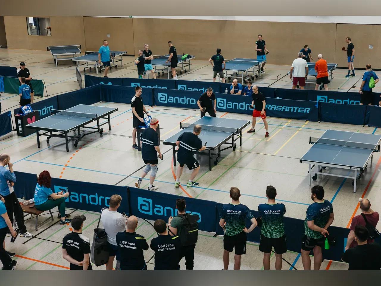 Teilnehmer:innen des Thüringer Firmencups spielen Tischtennis in einer Halle