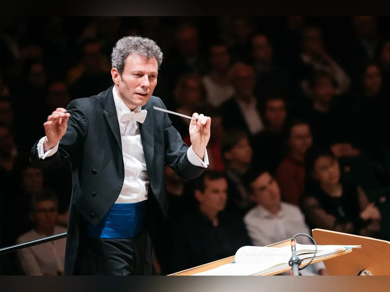 Simon Gaudenz steht am Dirigentenpult und dirigiert.<br>
