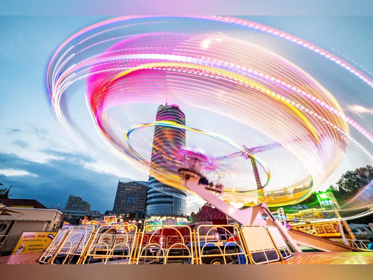 Aufnahme eines Fahrgeschäfts vor dem Jentower, bei dem die Lichter verschwimmen.