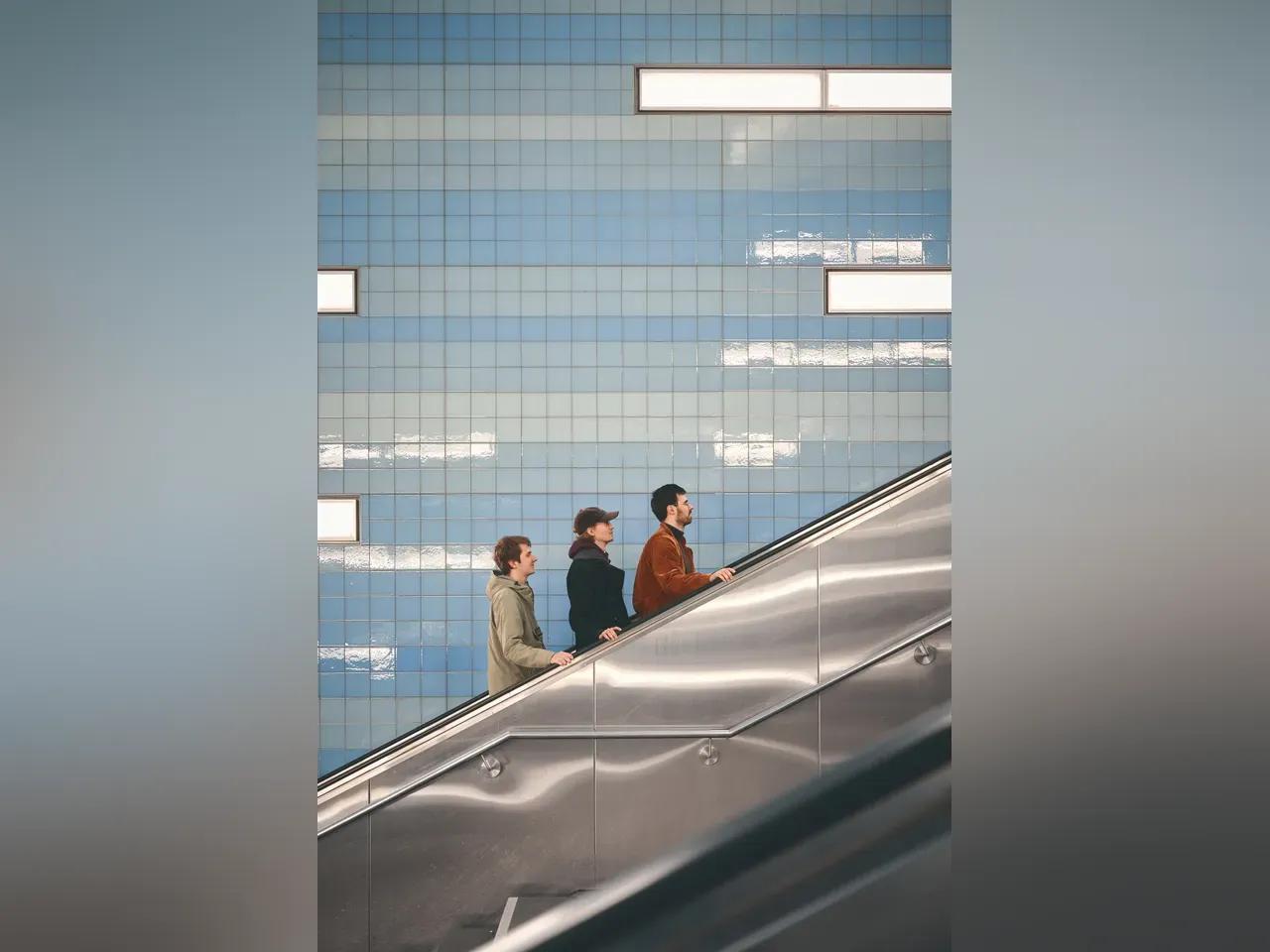 Drei Menschen auf einer Rolltreppe