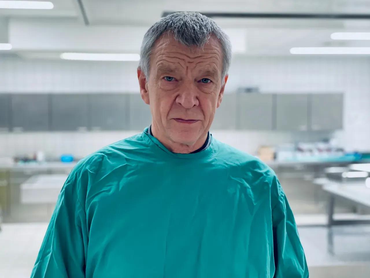 Prof. Dr. Klaus Püschel steht im grünen Kittel im rechtsmedizinischen Labor