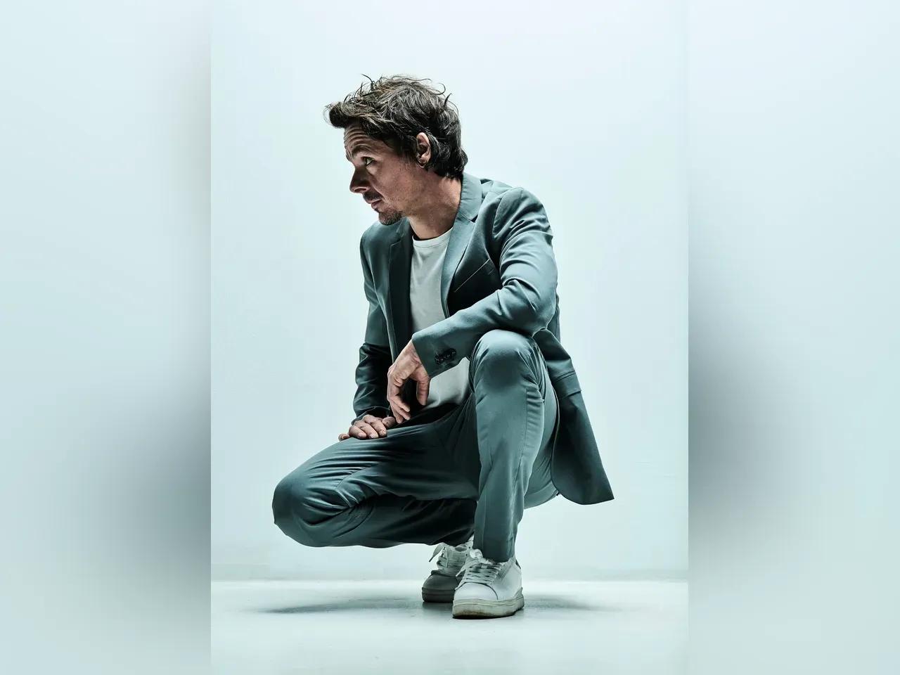 Carsten Schlegel im grauen Anzug hockt auf dem Boden