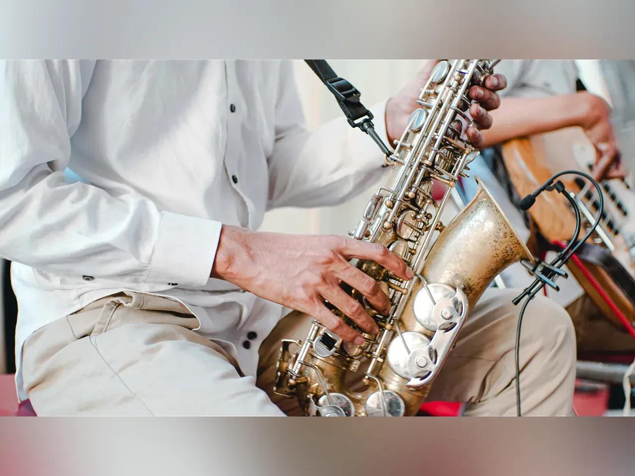 Eine Nahaufnahme von einem Saxophon, das von einem Musiker in einem weißen Hemd gespielt wird.