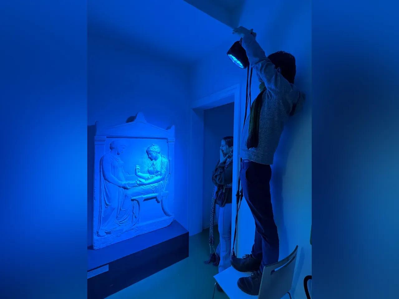 Ein antikes Relief wird mit Strahlern blau beleuchtet