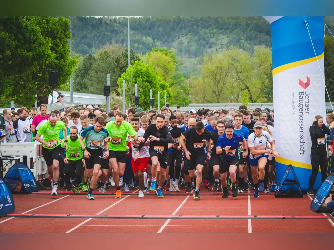 Viele Läufer:innen auf einer Aschebahn am Startpunkt beim Loslaufen. 