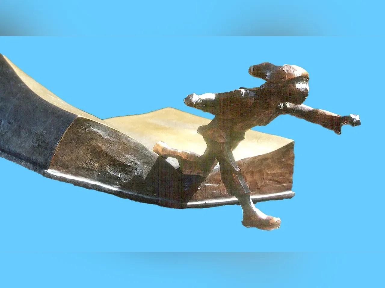 Bronzeplastik eines kleinen Männleins, das aus einem Buch steigt