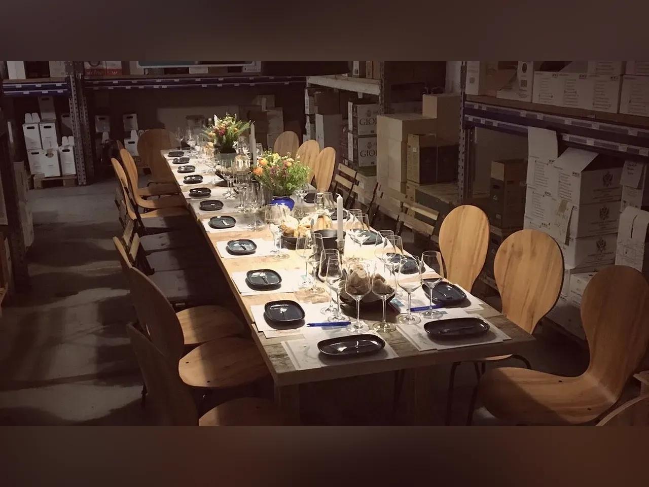 Gedeckte Tafel mit Geschirr, Weingläsern und Blumen im Weinlager von Wein-erlesen