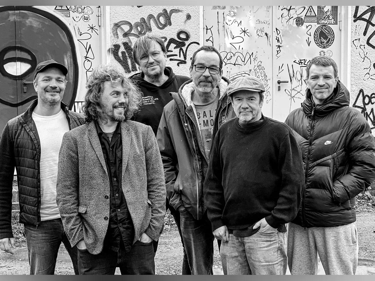 Schwarz-weiß Foto der Band Monsters of Liedermaching, die vor einer Graffitiwand steht