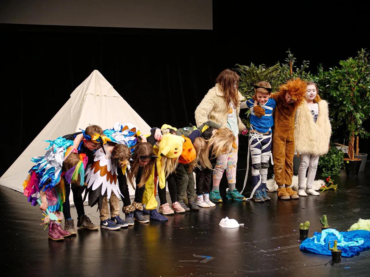 Kinder in bunten Kostümen verneigen sich auf der Bühne 