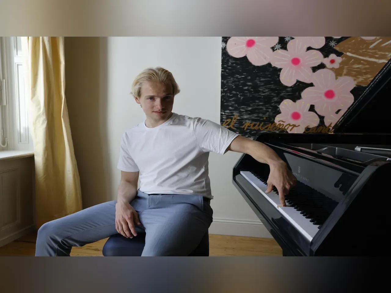 J. Konstantin Frantz sitzt lässig an seinem Klavier und drückt eine einzige Taste