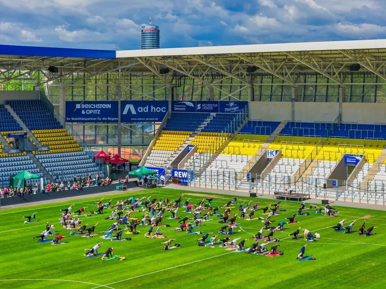Drohnenaufnahme ins Stadion mit Menschen, die Yoga machen