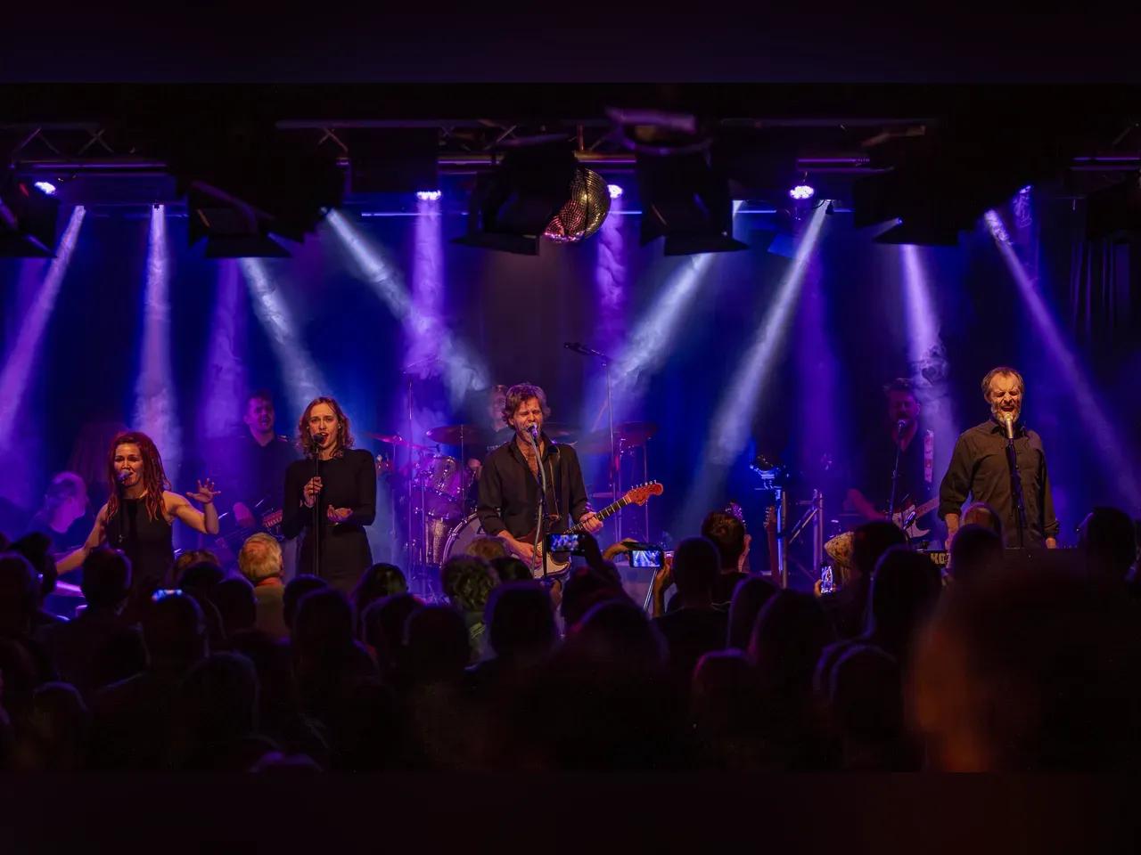 Die Band Distant Bells auf einer Bühne bei einem Konzert mit blauen Scheinwerfern