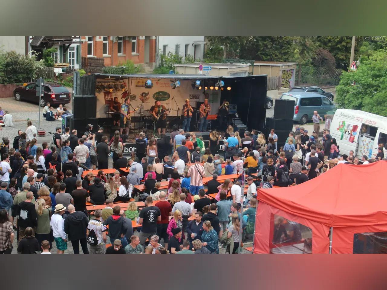 Eine Band spielt auf einer Bühne und Menschen stehen im Publikum in Jena West