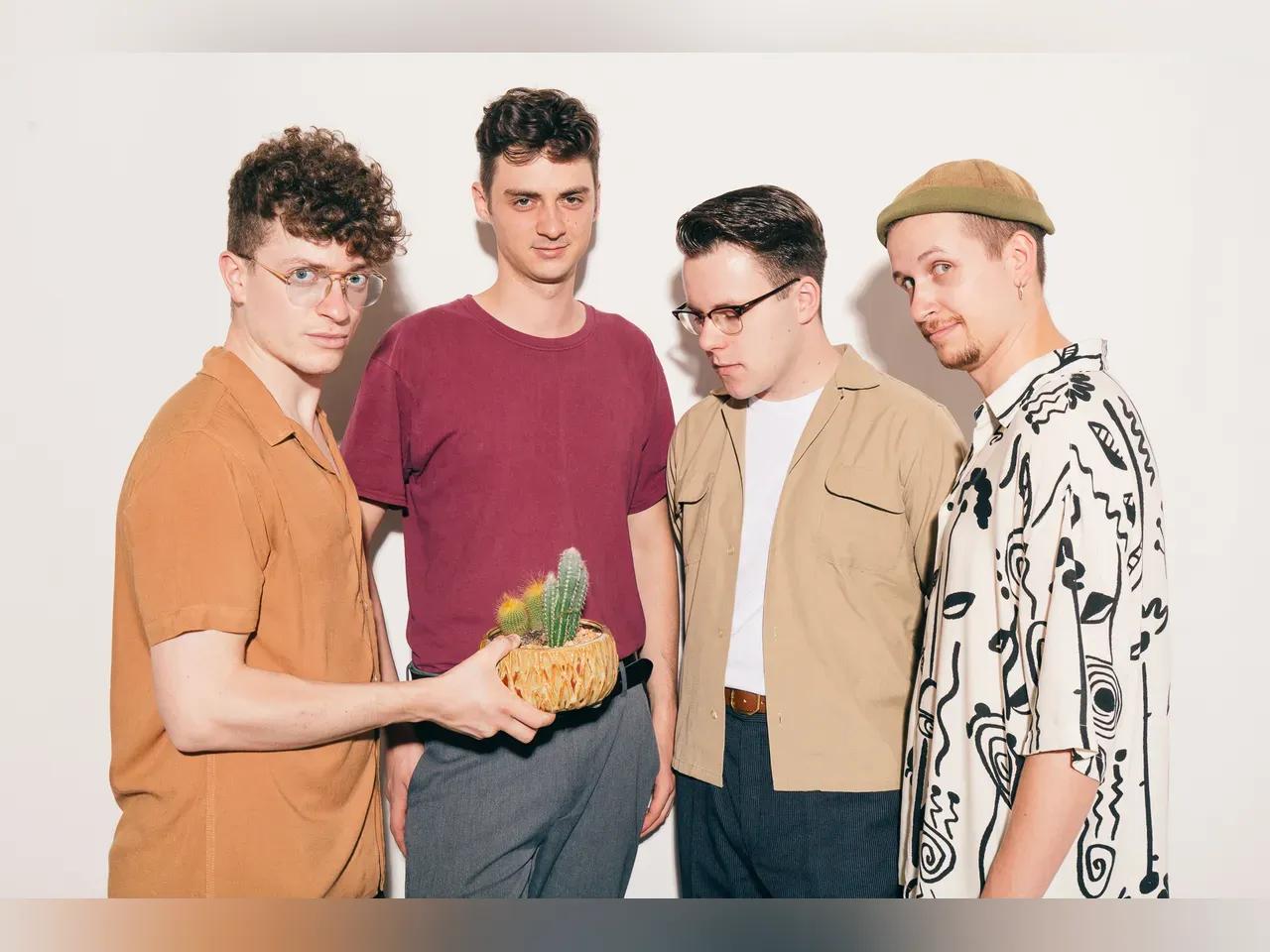 Vier Bandmitglieder mit einem kleinen Kaktus