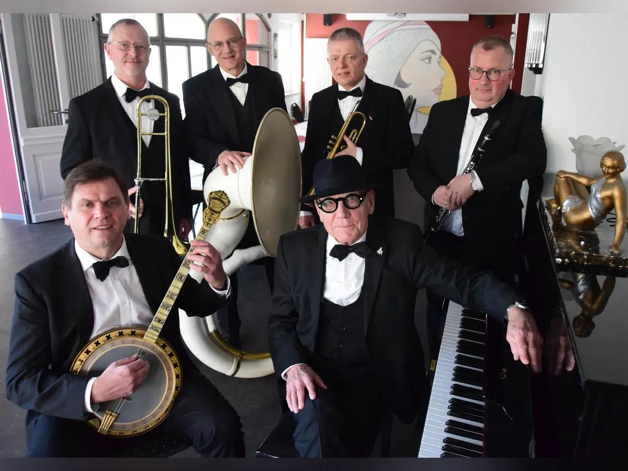 Mitglieder der Old Time Memory Jazzband in schwarzen Anzügen und Fliegen mit ihren Instrumenten