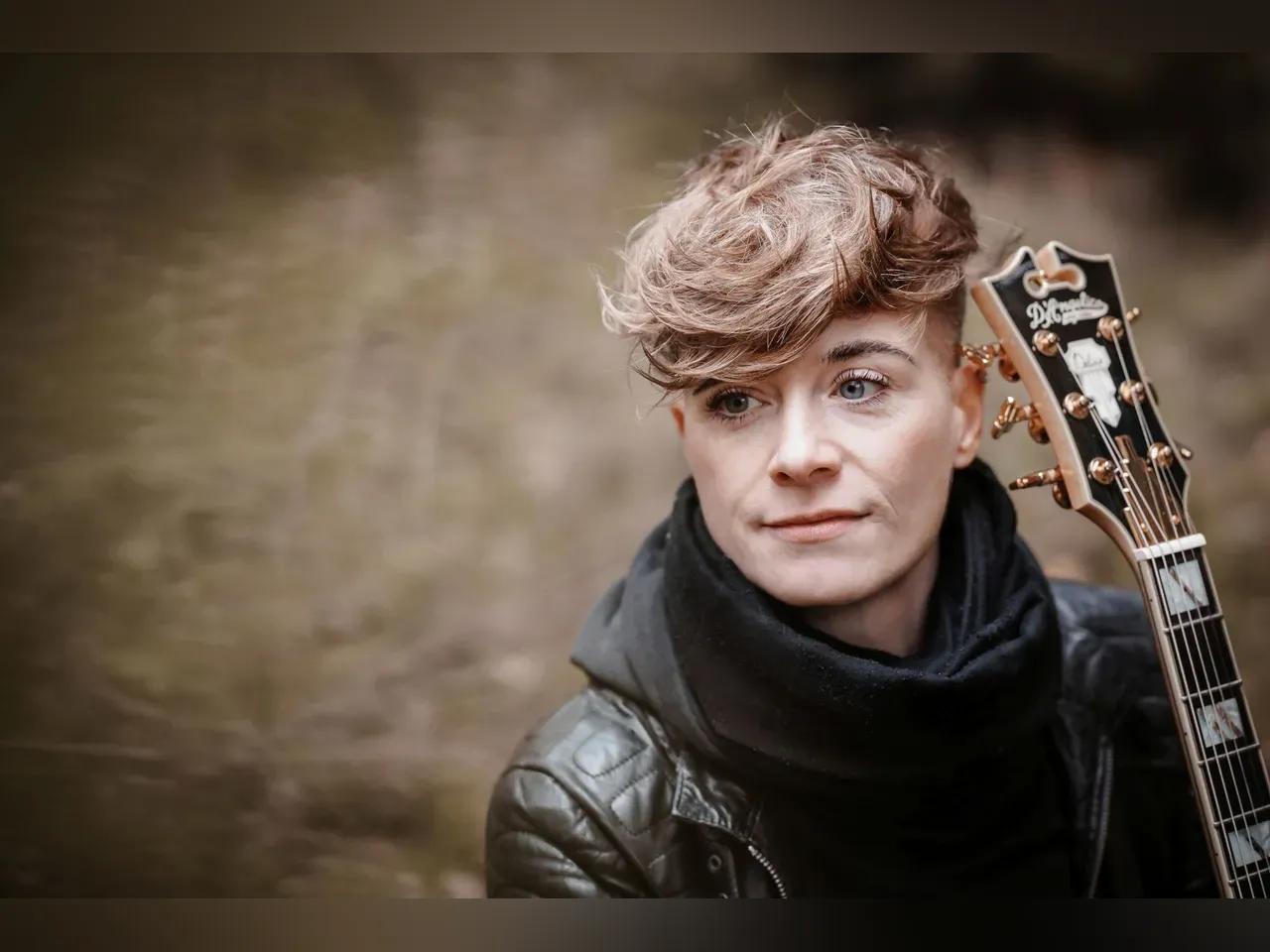 Portrait von Anna Heimthal, die ihre Gitarre in der Hand hält