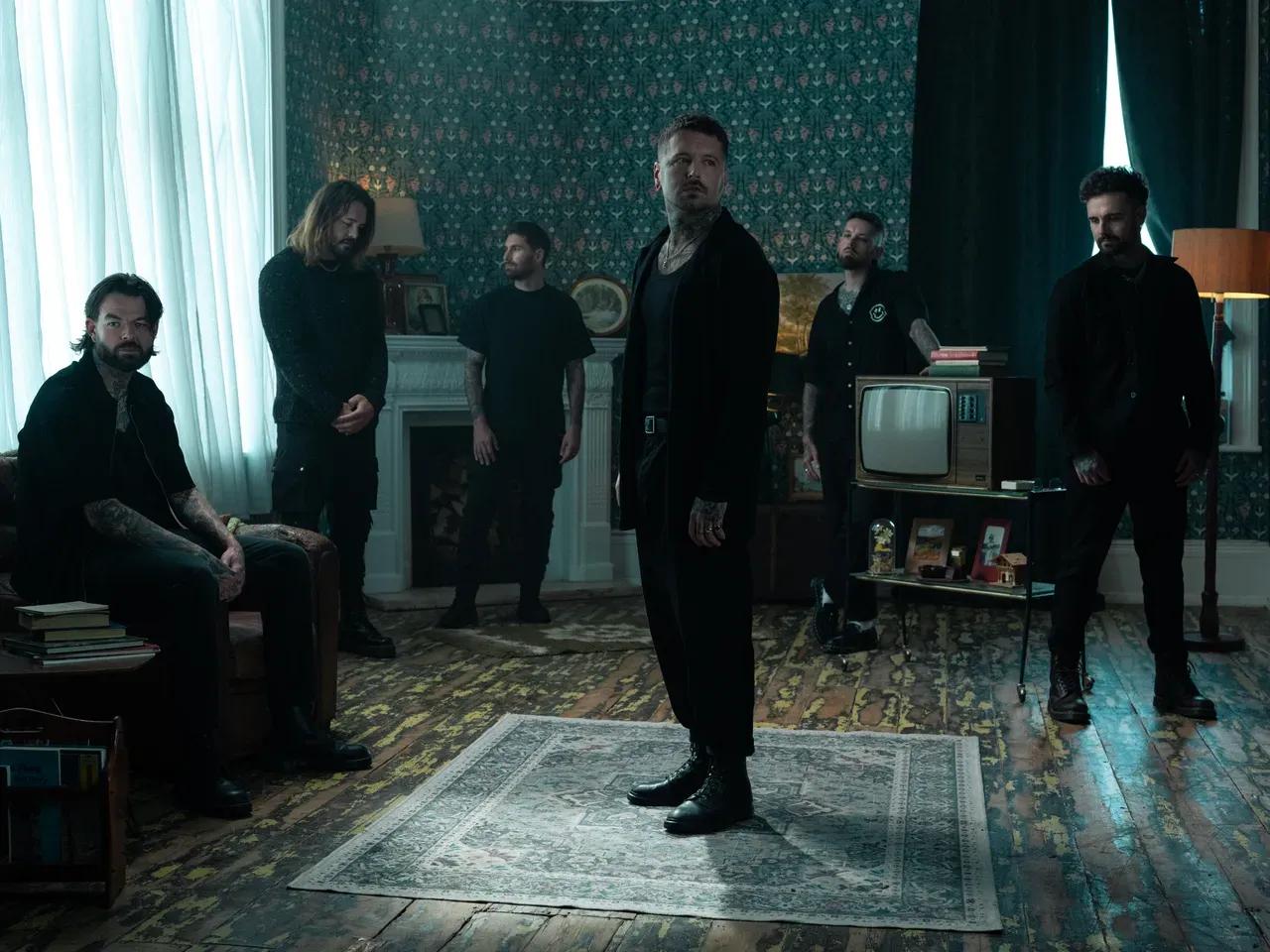 Bandmitglieder von Bury Tomorrow stehen verstreut in einem Wohnraum mit Kamin, dunklen Vorhängen und altem Fernseher
