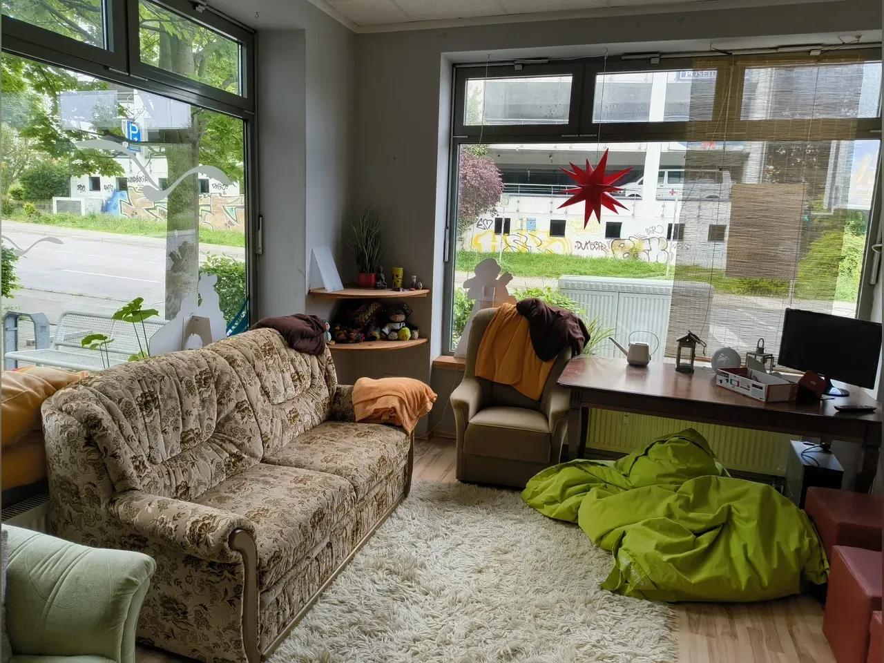 Blick in den Veranstaltungsraum mit großen Fenstern und gemütlichen Sofas und Sesseln