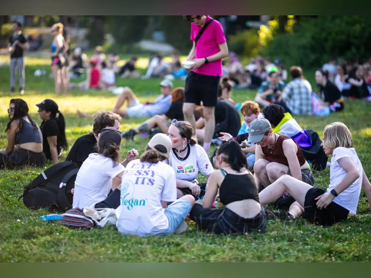 Junge Menschen sitzen auf einer Wiese und unterhalten sich