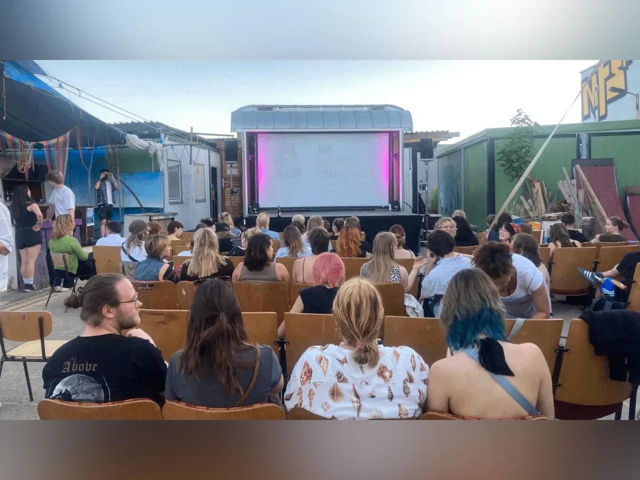 Kinoleinwand und Besucher:innen auf dem Gelände des Kulturschlachthofs Jena