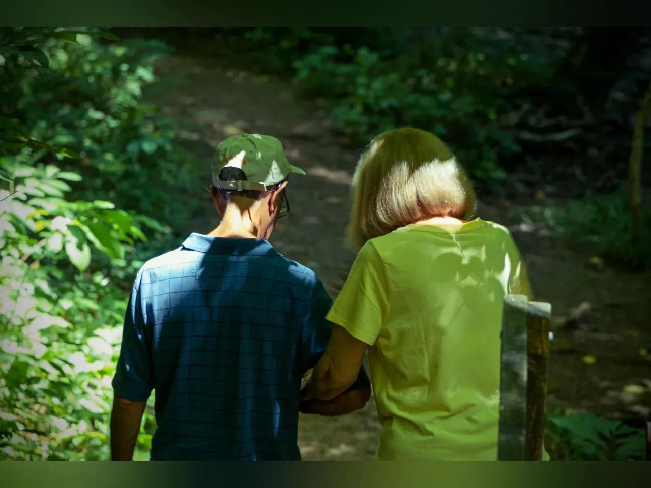 Zwei Menschen gehen einen Weg entlang und haben die Arme beieinander eingehakt