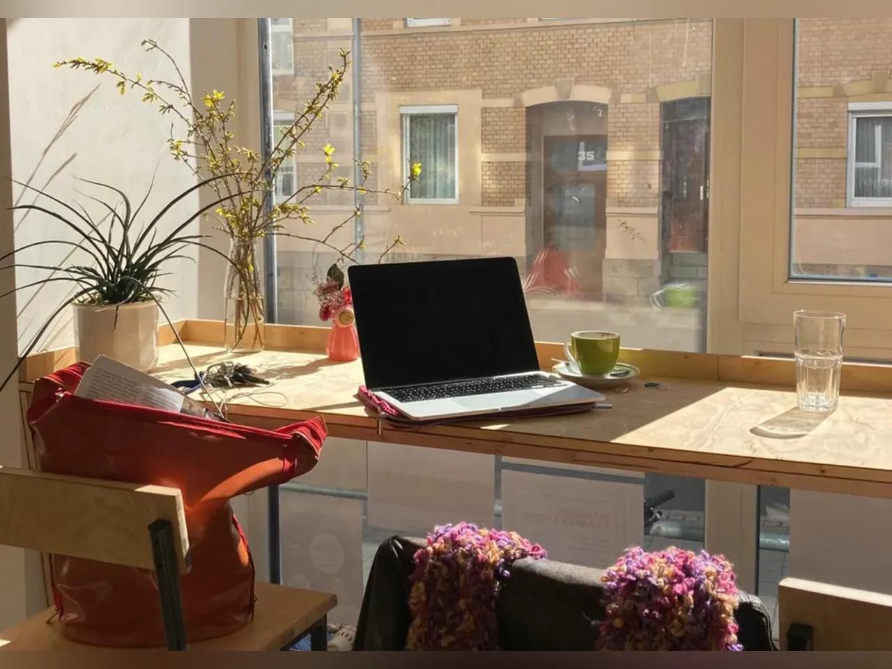 Laptop steht aufgeklappt auf einem Tisch am Fenster