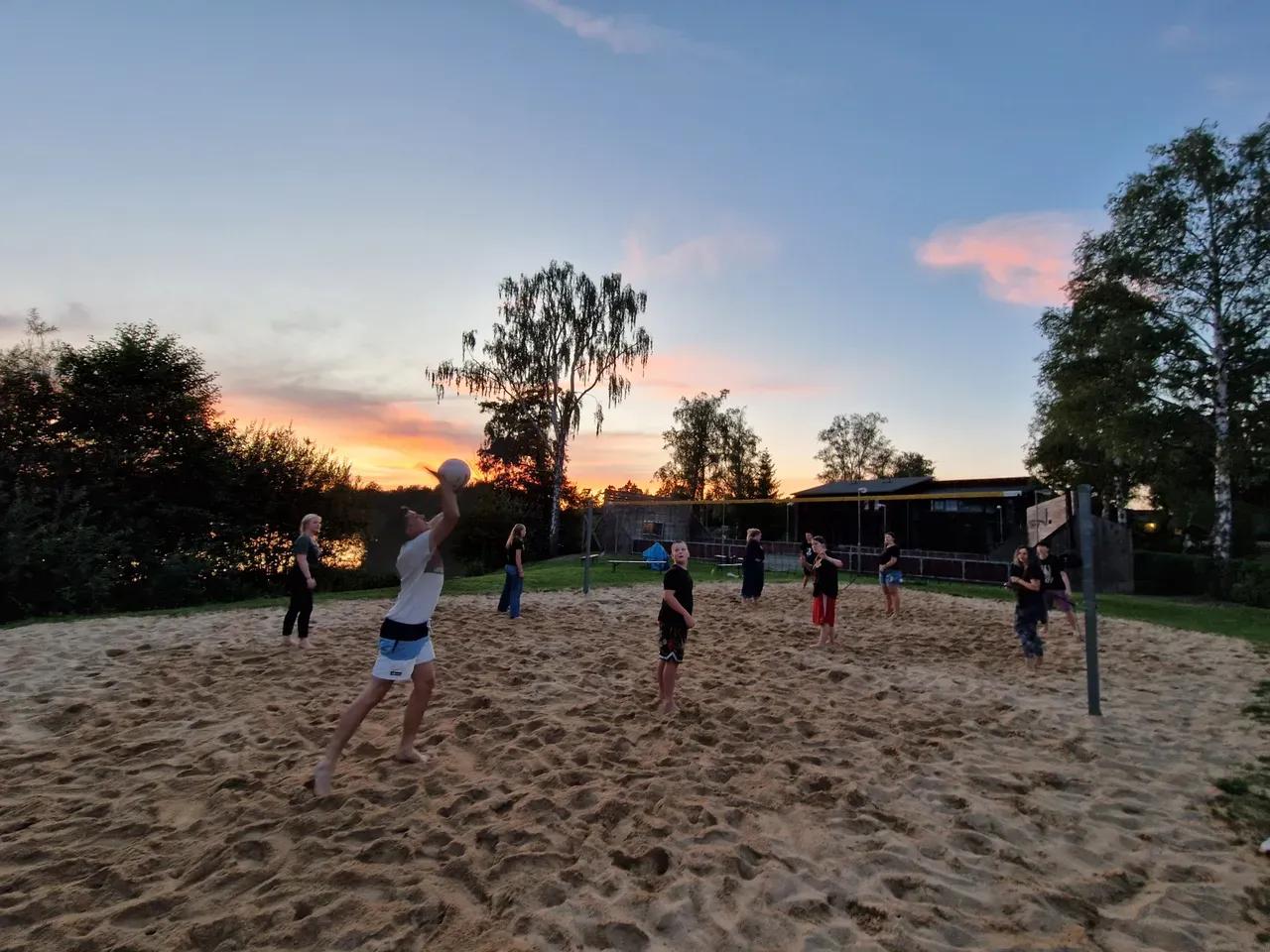 Jugendliche spielen Beach-Volleyball in der Abenddämmerung