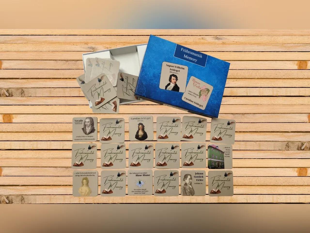 Zu sehen ist ein Holztisch, auf dem ein Memoryspiel aufgebaut ist, welches den Titel "Frühromantik-Memory" trägt. 