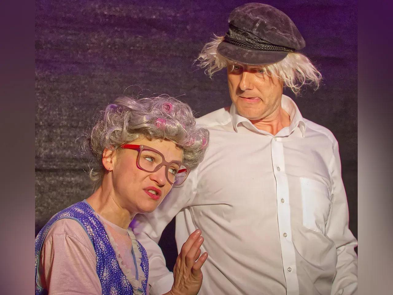 Zwei Schauspieler:innen mit Perücken und Kostümen