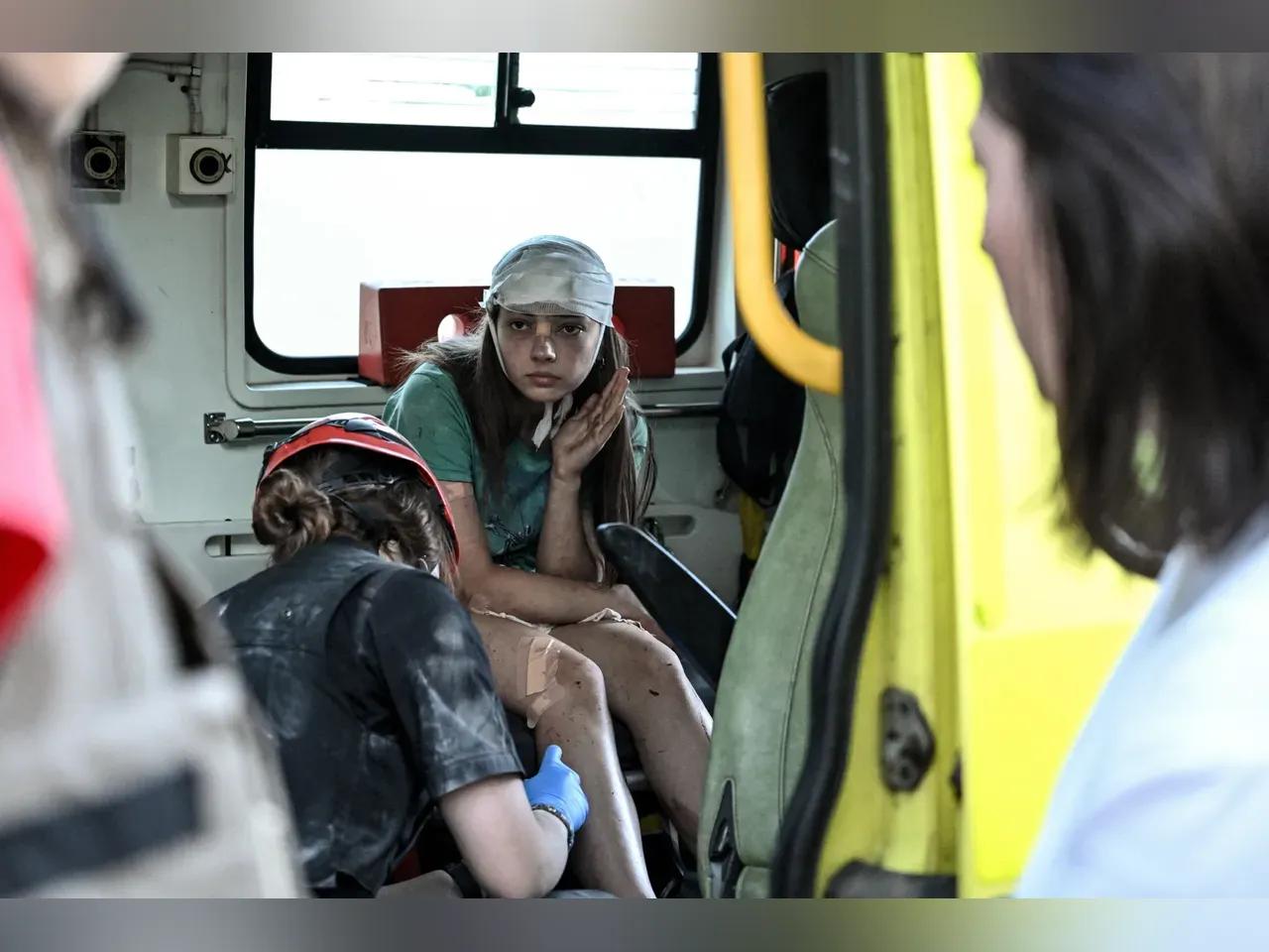 Junge Frau mit Verletzungen und Bandagen lässt sich von einer Rettungskraft verarzten