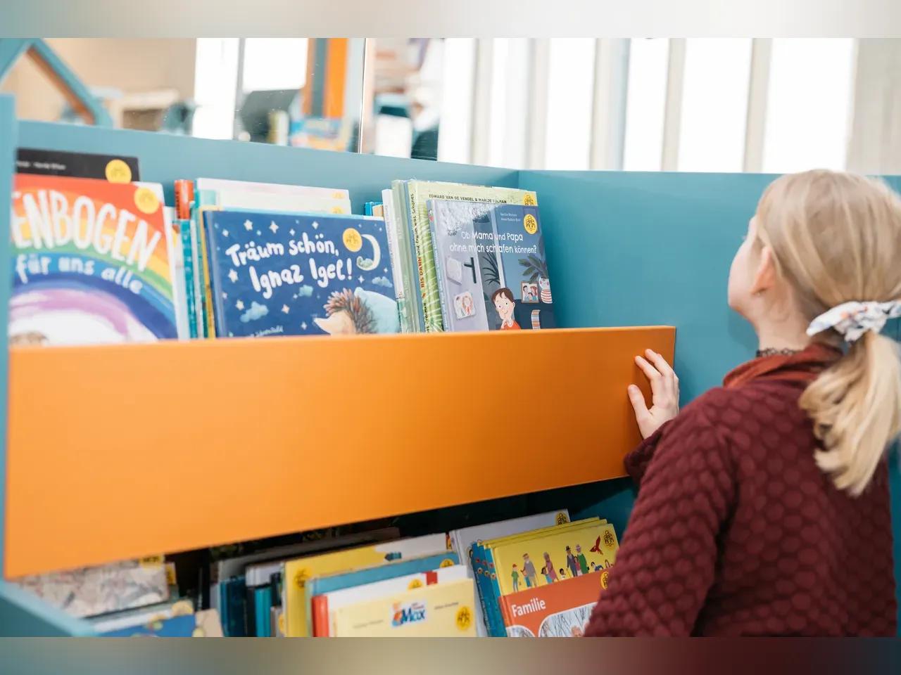 Kind sucht Bücher in einem Bücherregal