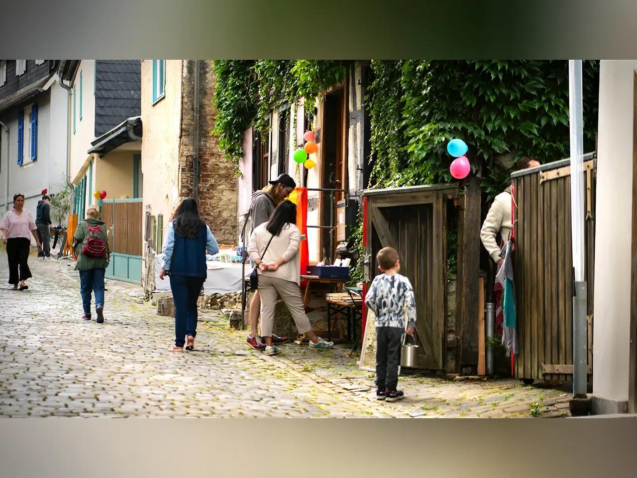 In einer gepflasterten Gasse verweilen Passanten, um sich den Hofflohmarkt anzusehen.